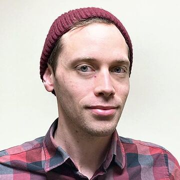 A headshot of Mike Trilling wearing a red shirt and hat. 