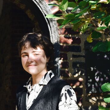 A portrait of a person standing and smiling outdoors