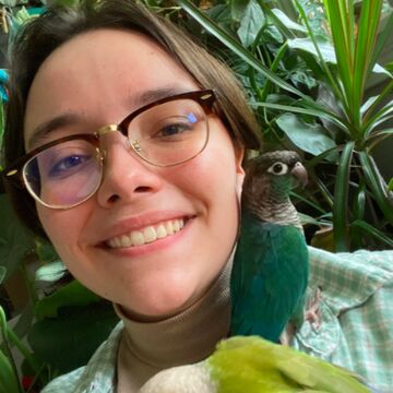 A person smiling outdoors with two birds