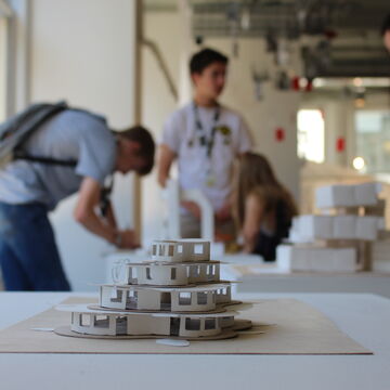 A small model of a building with a group of young students in the background.