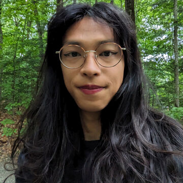 Selfie of a person standing outdoors in front of greenery