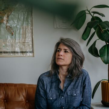 Carla wears a denim shirt and looks off to her right.