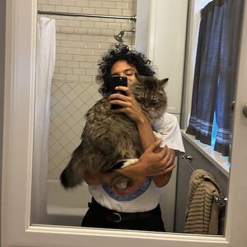 Isaac holds a large cat in a bathroom.