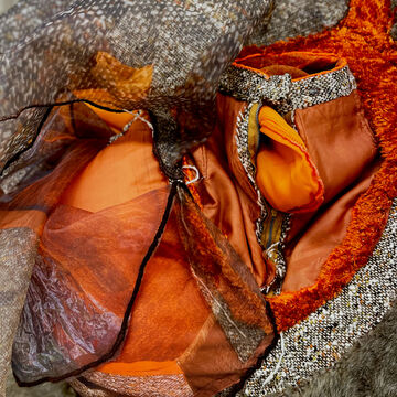 Detail shot of fiber manipulation in orange, biege, brown textiles.