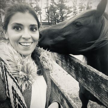 Selfie of a person with a horse kissing their cheek