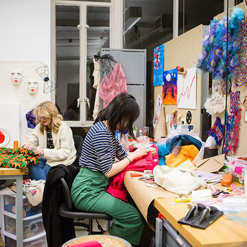 Two students work on fashion garments in a shared studio