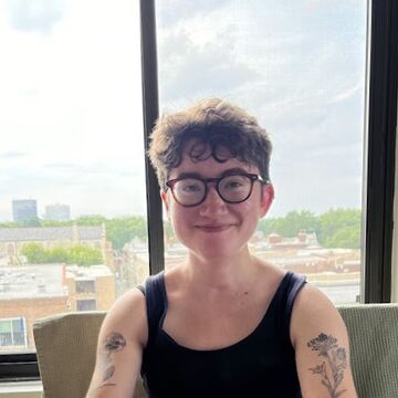 Portrait photograph of Llewyn Blossfeld in front of a window overlooking a city