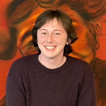 Portrait photograph of Seth Indigo Perry in front of orange painting