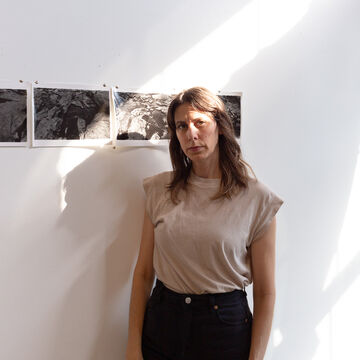 Portrait of a white woman standing in front of artwork in a gallery space