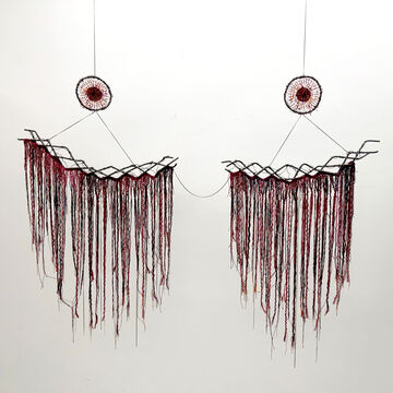 An installed and suspended fiber art work representing a chest. Two braided steel wires hold red fringe and are suspended by two circle weavings.
