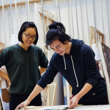Two Asian students looking at an artwork