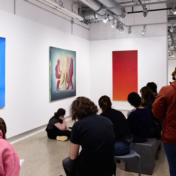 A group of students looking at colorful artwork in a gallery