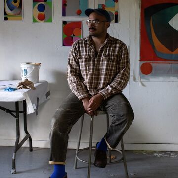 Michael Cuadrado Gonzalez, a Puerto Rican artist and SAIC faculty member, seated in a studio space.