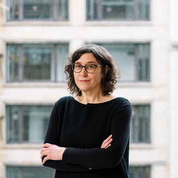 Headshot of Melanie Emerson, a fair-skinned person with short dark wavy hair and glasses.
