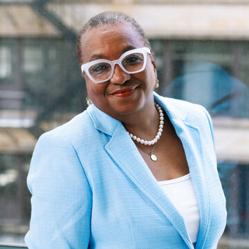 Portrait of Jacqueline Williams, an adult Black woman wearing a pulled back hairstyle and glasses.