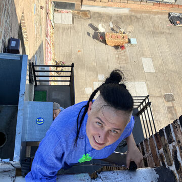 Irina Bucan, an adult person with a fair skin tone and a black skullet, climbing a fire escape.