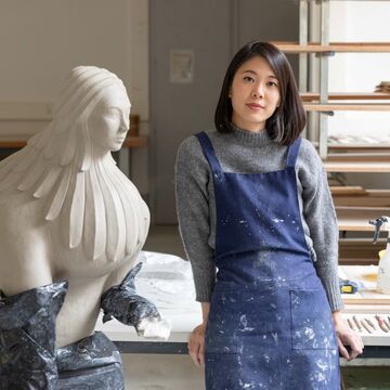 Portrait of Pei-Hsuan Wang, an adult Taiwanese-American person with a medium-fair skin tone and dark shoulder-length hair, in an art studio space.