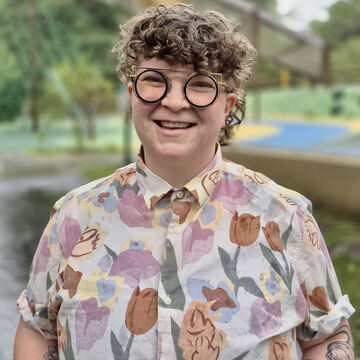 SAIC faculty member Ali Blake with light skin tone, curly hair, and glasses.