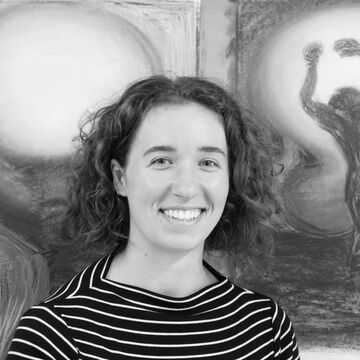 Black and white headshot of Emma Stine, an adult person with a fair skin tone and short curly hair.