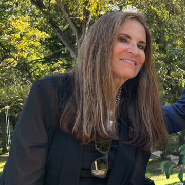 SAIC faculty member Nan Stein, with light skin tone and brown hair, stands outside.