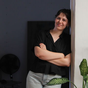 SAIC faculty member Julieta Beltran Lazo, a person with light skin and dark hair standing in a doorway.