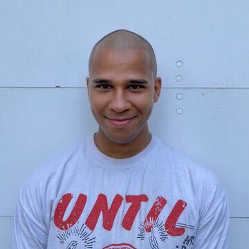 Tony Williams, an adult Black person with a medium-dark skin tone and close-shaved head, smiling outdoors.