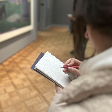 A student with a sketchpad inside a museum.