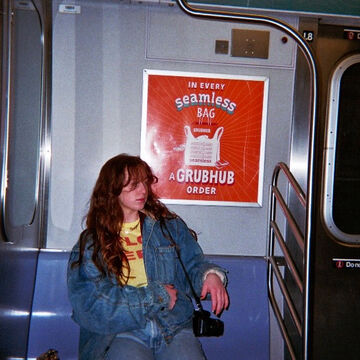 Carly Seymour, an adult person with a fair skin tone and red hair, sitting on the train.