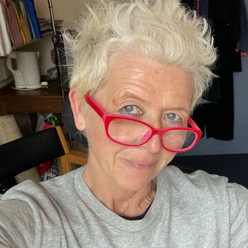 Selfie of Sara Jane Bailes, an adult person with a fair skin tone, short blonde hair and red glasses.