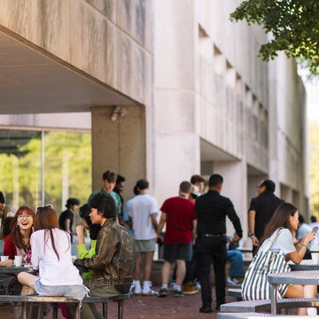 Students sit at tables outside of the 280 Building on SAIC's campus.