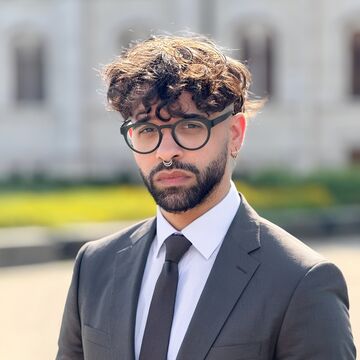 Headshot of David Diaz, an adult person with a medium-fair skin tone, dark curly hair, and glasses.