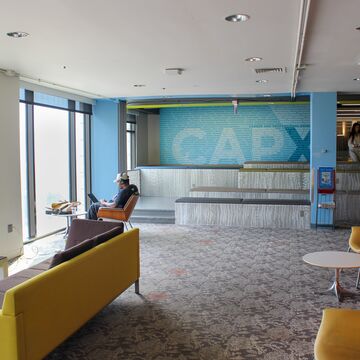 A student sits with headphones on looking at a laptop facing a window.