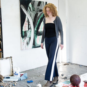 Jessica Zawadowicz, an adult person with a fair skin tone and curly ginger hair, standing in a studio space.