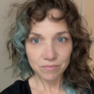 Selfie of Melanie P. Brown, an adult person with a fair skin tone and wavy brown and blue hair. 