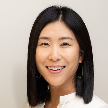 Headshot of Younsoo Kim Flynn, an adult Asian person with a medium-fair skin tone and short dark hair. 
