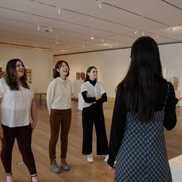 Four adults of varying ethnicities and genders view a sculpture in the Art Institute.