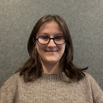 Headshot of Audra Greavu, an adult person with medium-short hair, a fair skin tone, and glasses. 