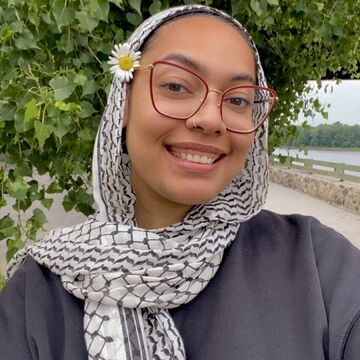 Selfie of Jannah Sellar, an adult person with a medium-dark skin tone, glasses, and a keffiyeh. 