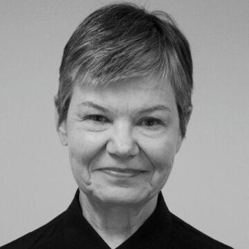 Black and white headshot of Kate Schutta, an adult person with a fair skin tone and pixie cut. 