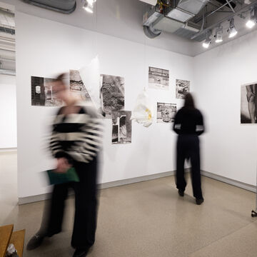 Two blurry people view art in a gallery. 