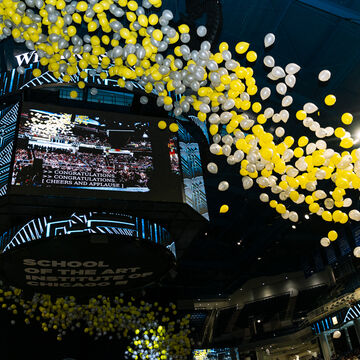Yellow and gray balloons releasing in an arena. 