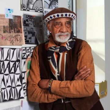 Robert Earl Paige standing against a wall with artwork.