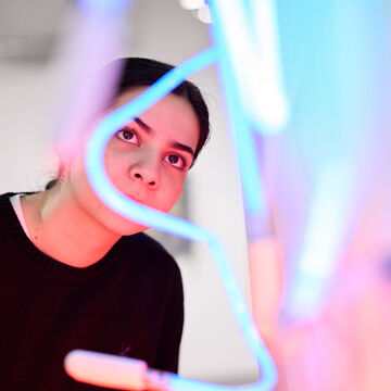 A person views a neon light artwork. 