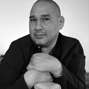 Black and white headshot of David Antonio Cruz, an adult person with a medium-fair skintone. 