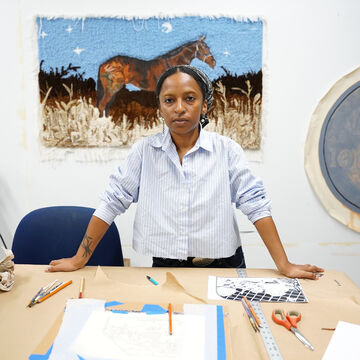 Ahmad George, an adult person with a medium-dark skintone in a studio space. 