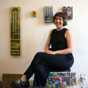 Arden Henderson, an adult person with a fair skintone, seated in a studio space. 