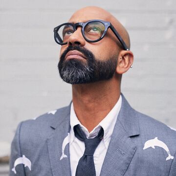 Image of artist Brendan Fernandes, speaker for SAIC's 2026 Low-Residency MFA Commencement. Brendan is wearing a suit and looking up and to the left of the camera frame.