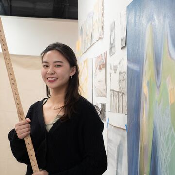 Headshot of Winnie Weiyun Szu, an adult Asian person with a fair skintone, holding a meter stick. 