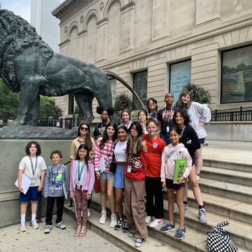 Middle school students of varying ethnicities, skintones, and genders, gathered on the steps of the Art Institute of Chicago. 