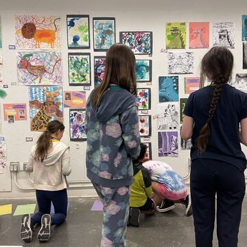 Middle school students of varying ethnicities, skintones, and genders, viewing artwork in a studio space. 